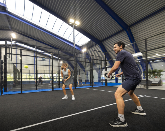 Due persone giocano una partita di padel su un campo indoor.