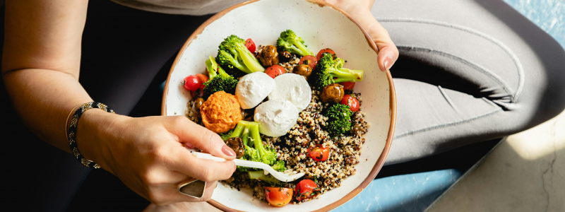 Bowl con quinoa, broccoli, pomodorini e mozzarella, esempio di pasto sano ed equilibrato.